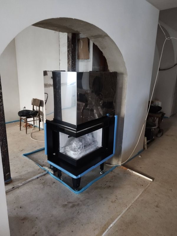 Rohová krbová vložka v procesu instalace